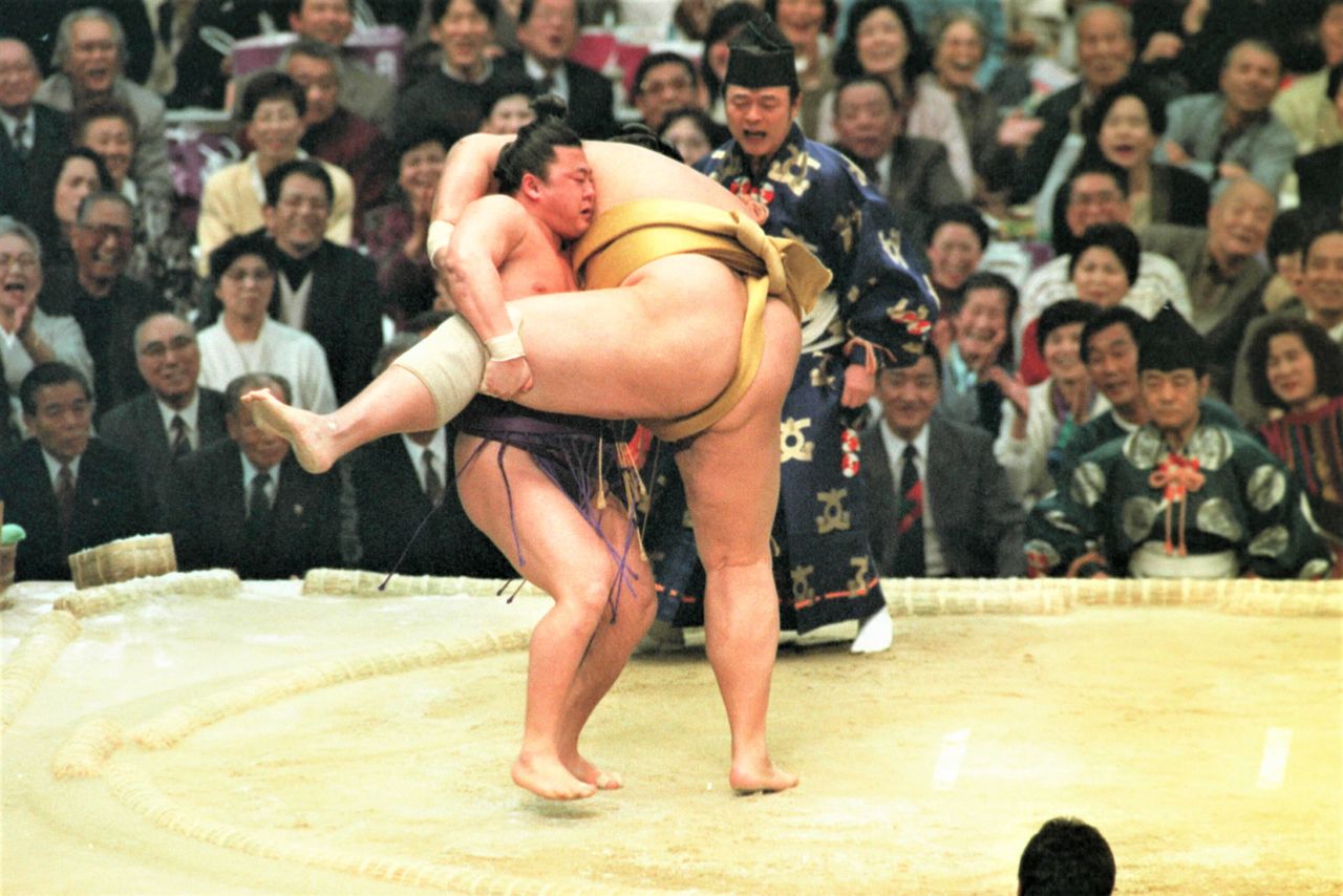 In this 1993 match against Mitoizumi, Mainoumi (at left) used his low center of gravity effectively to grab a leg and down his much larger opponent. “In sumō, the key to winning is getting your opponent off-balance.” Taken on March 17, 1993, at the Osaka Prefectural Gymnasium. (© Jiji)