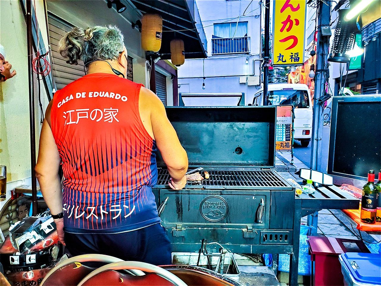 Eduardo grilling asado on a barbecue outside his restaurant. (© Kumazaki Takashi)