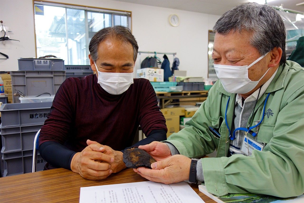 Professor Nagasawa Kaya (left) and Fukuda Makoto of the Kamakura municipal government’s cultural properties division. The fragment of wood in Fukuda’s hands is thought to be part of a Buddhist image. (© Mochida Jōji)