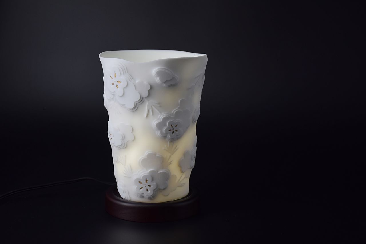 A porcelain lamp shade with raised flower and bamboo design.