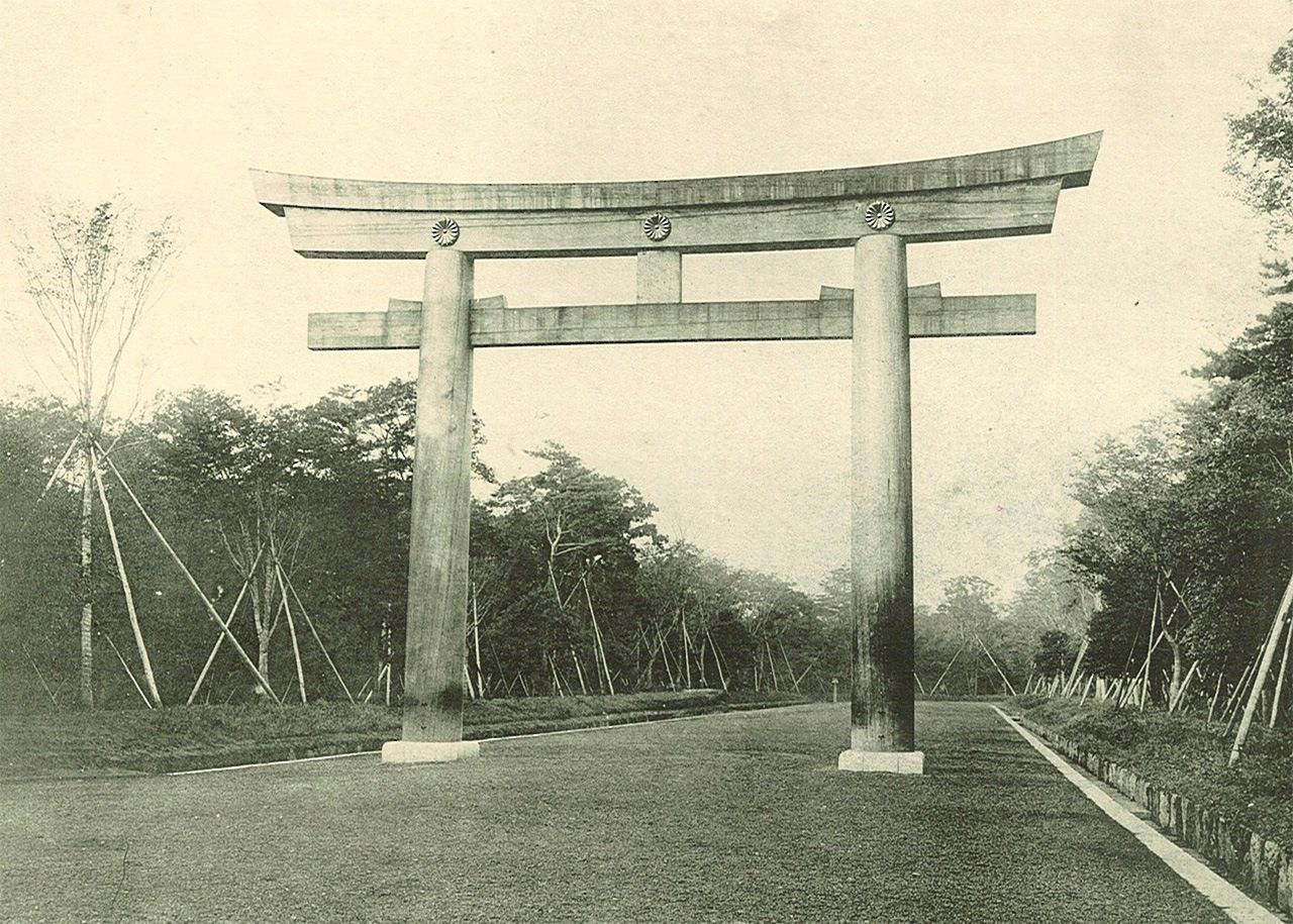 A giant wooden torii towers over the newly planted forest during the construction of Meiji Shrine.