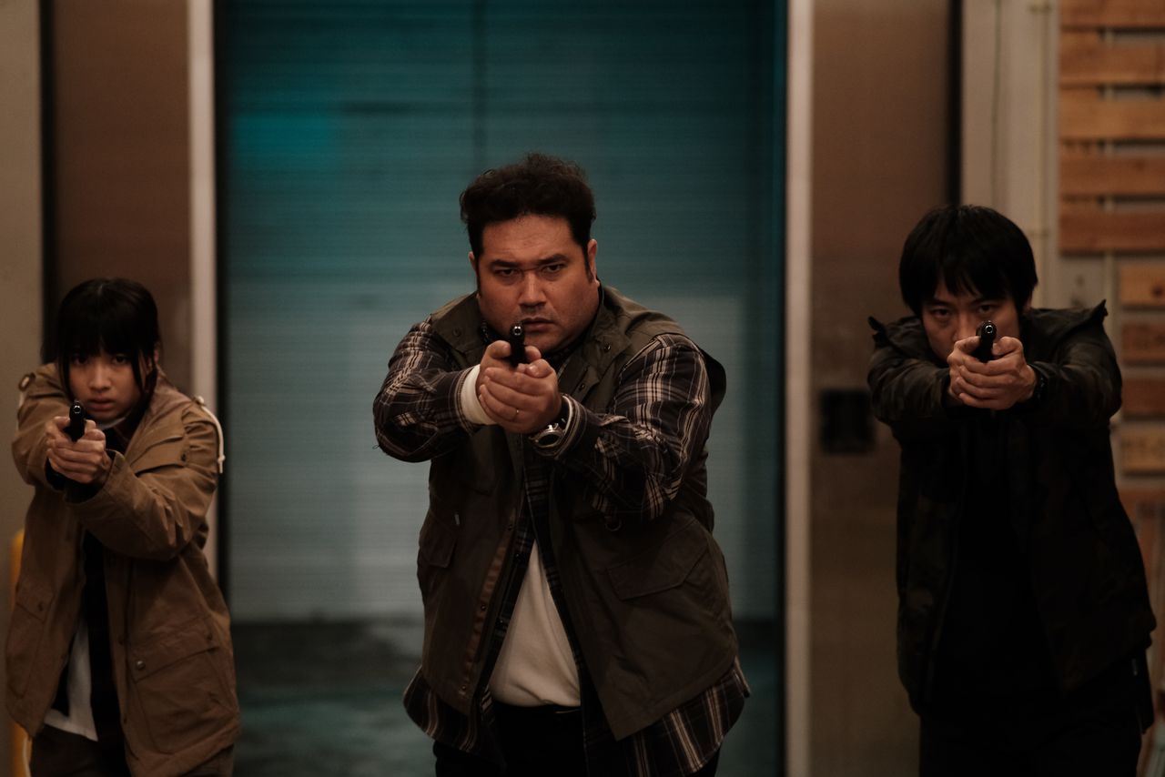 Torada and his team fighting the bad guys. At left is Sakanoue Akane. (© 2022 Bad City Production Committee)