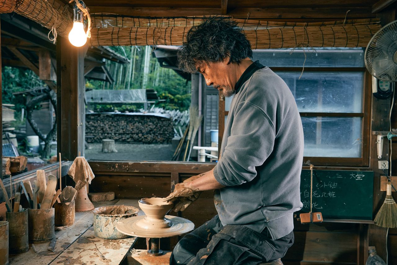 Seiji (Yakusho Kōji) is a potter creating in his home workshop. (© 2022 Familia Production Committee)