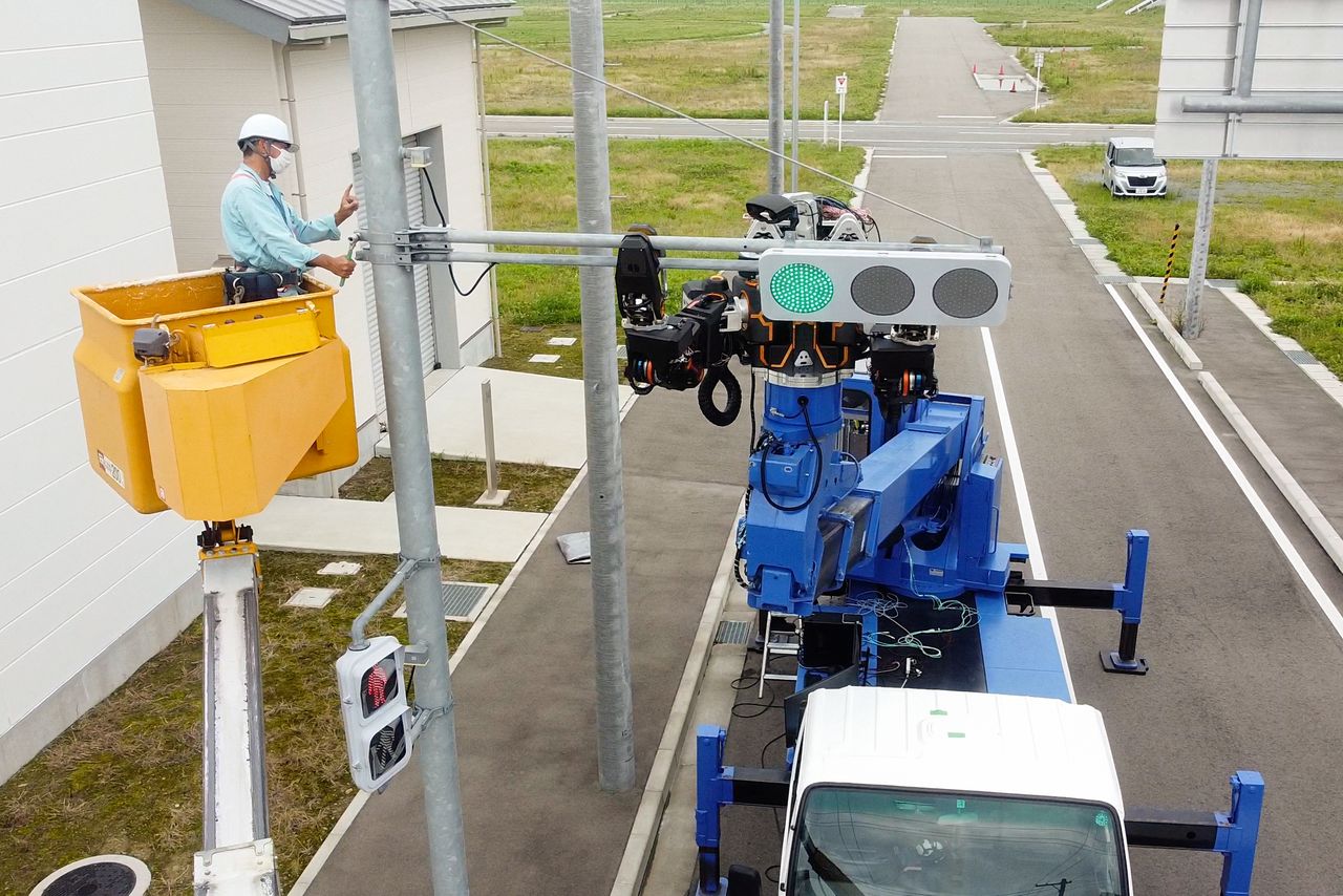 The JINKI type Zero installs traffic lights at the Robot Test Field. (© Man-Machine Synergy Effectors)
