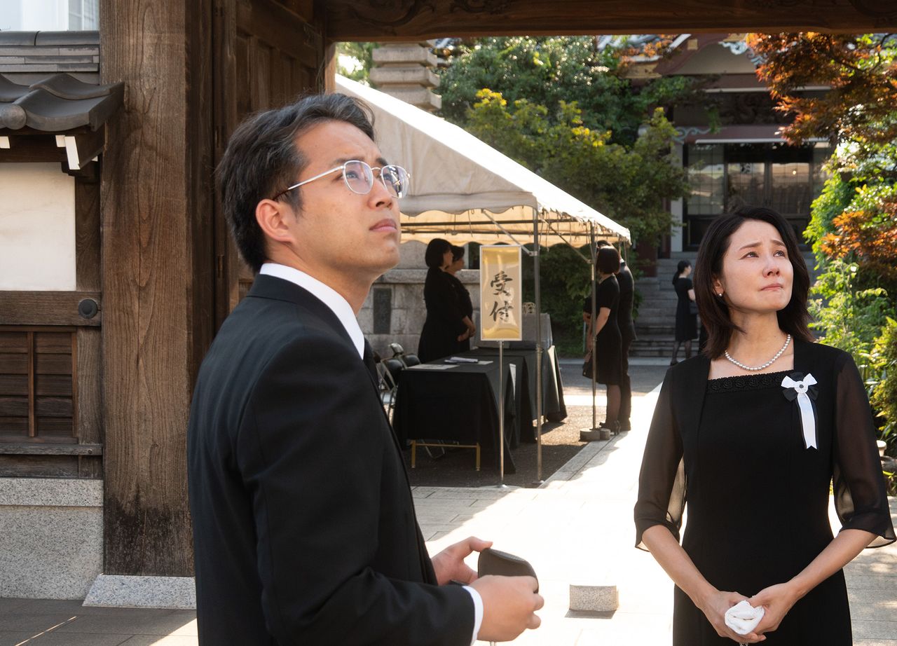 Isamu’s sister (played by Yoshida Yō) speaking with Dan (Miura Takahiro) at Isamu’s funeral. (© 2023 Winny Production Committee)