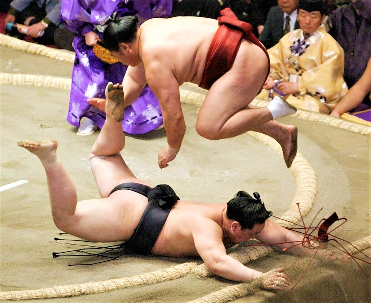 Kyokushūzan leaps clear of yokozuna Asashōryū at the last moment after pulling him to the ring floor on the ninth day of the 2003 summer tournament, earning him a coveted gold star for defeating a grand champion. (© Jiji)