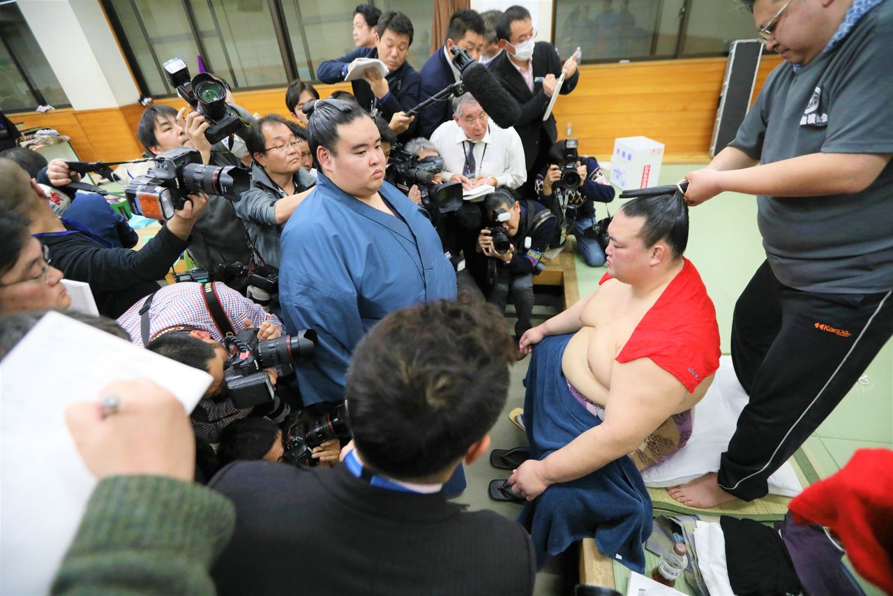 A grim-faced yokozuna Kisenosato, returning to the shitaku beya after hise second consecutive loss on day two of the January 2019 tournament, with his attendant holding off the press. Two days later, Kisenosato announced his retirement. (© Jiji)