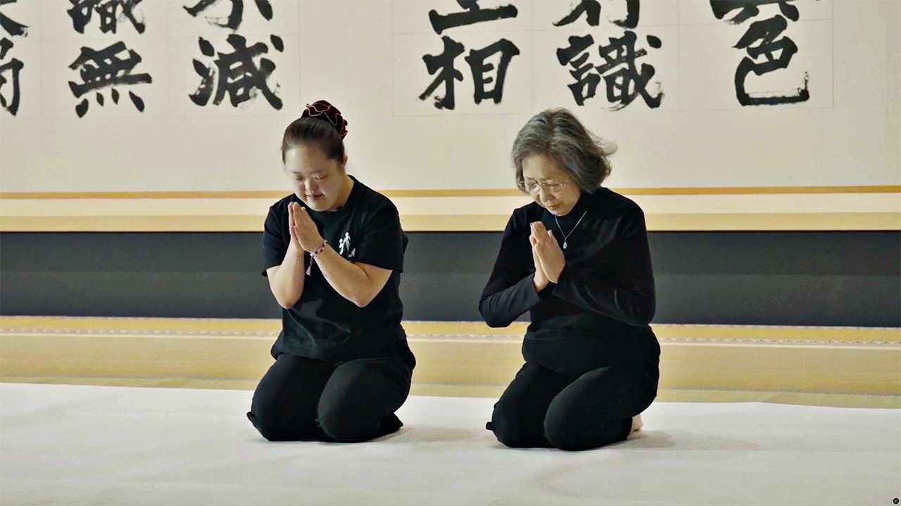 Shōko and her mother offer prayers before a calligraphy session in the prayer hall at Ryōunji, decorated with the “world’s biggest” Heart Sutra, in Shōko’s calligraphy. (© Masterworks)