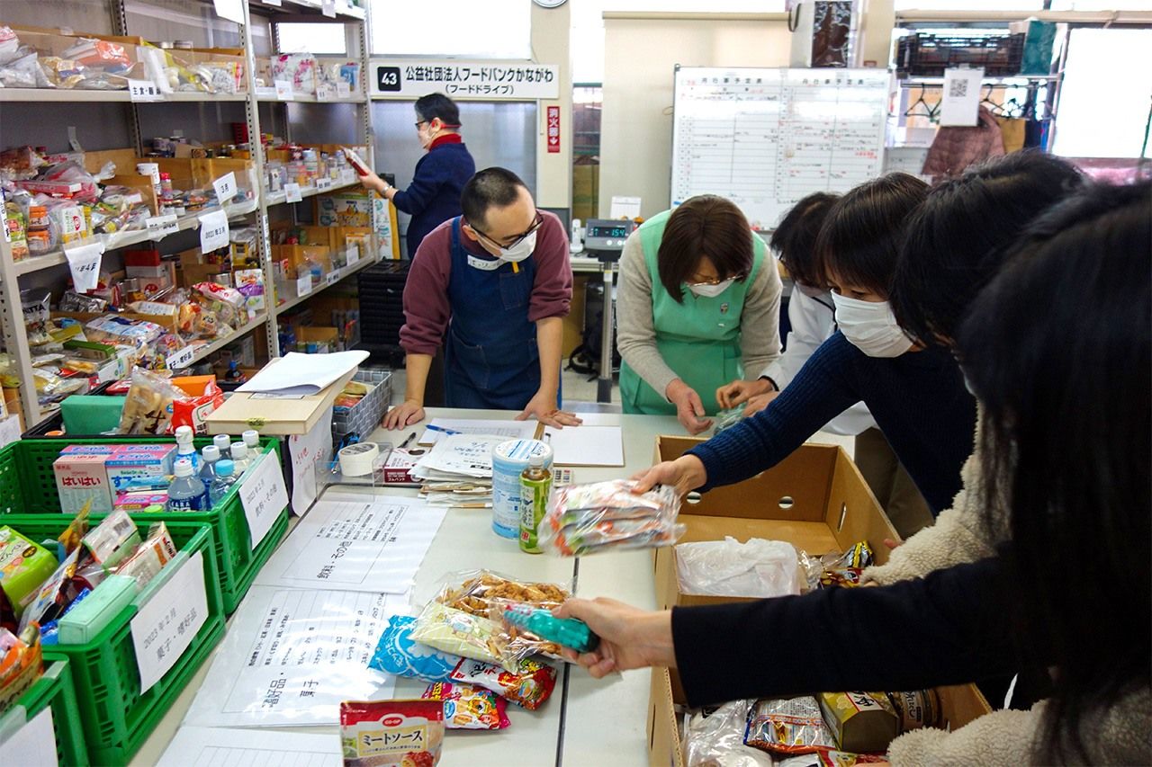 Volunteers sort food items by their use-by dates.