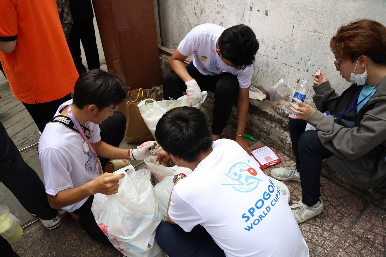A Vietnamese team sorting trash as they consult the rule book. (Courtesy of the SpoGomi World Cup Operating Committee)