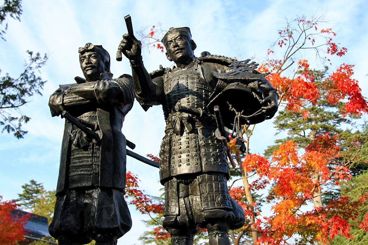 Statues of Uesugi Kagekatsu (left) and Naoe Kanetsugu at the ruins of Yonezawa Castle in Matsugamisaki Park, Yonezawa, Yamagata Prefecture. (© Pixta)