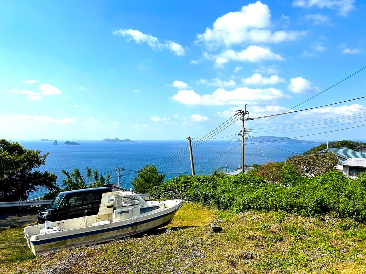The view from Kurosaki Church toward Karematsu Jinja. A lonely fishing boat sits in a yard. (© Amano Hisaki)