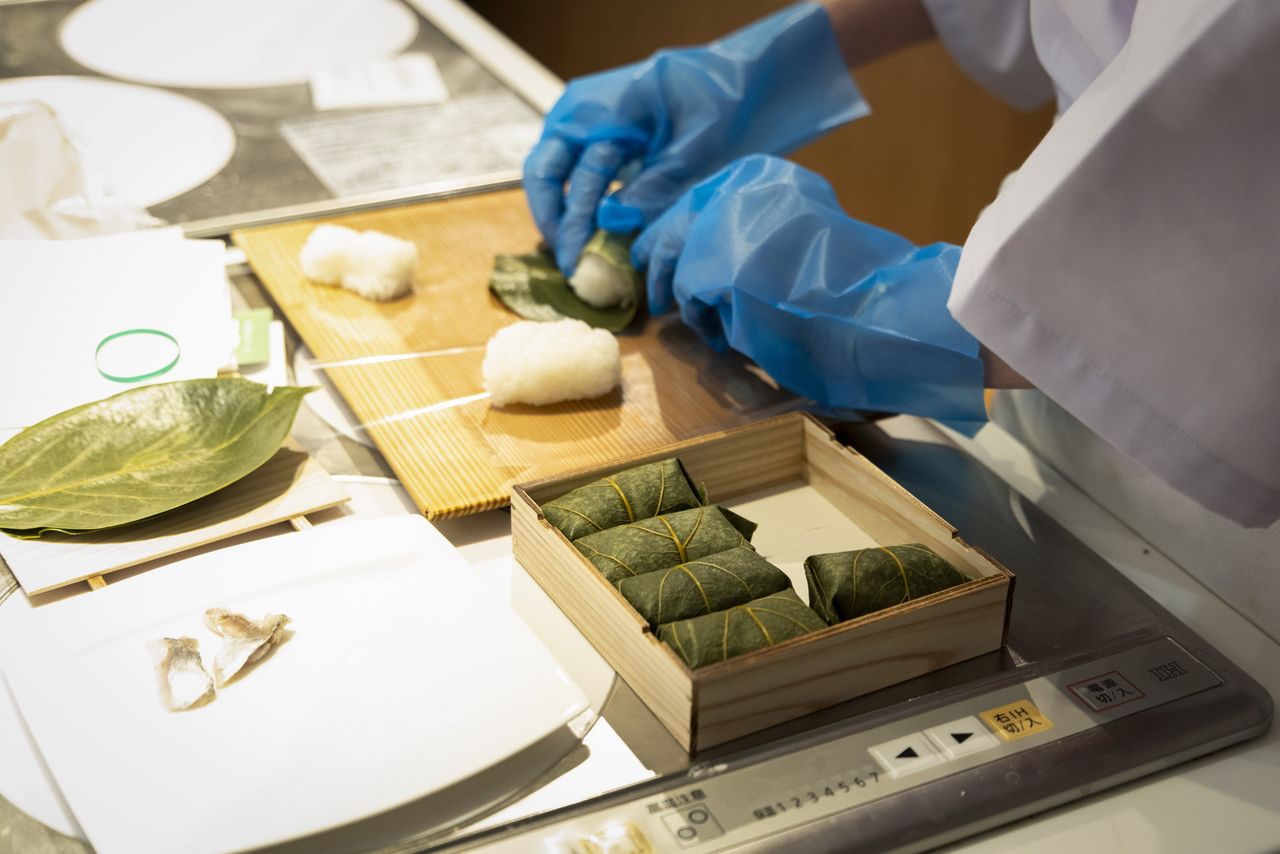 A participant prepares kaki-no-ha-zushi. According to Iida, veteran workers at Hirasō are able to wrap as many as 600 pieces in one hour.