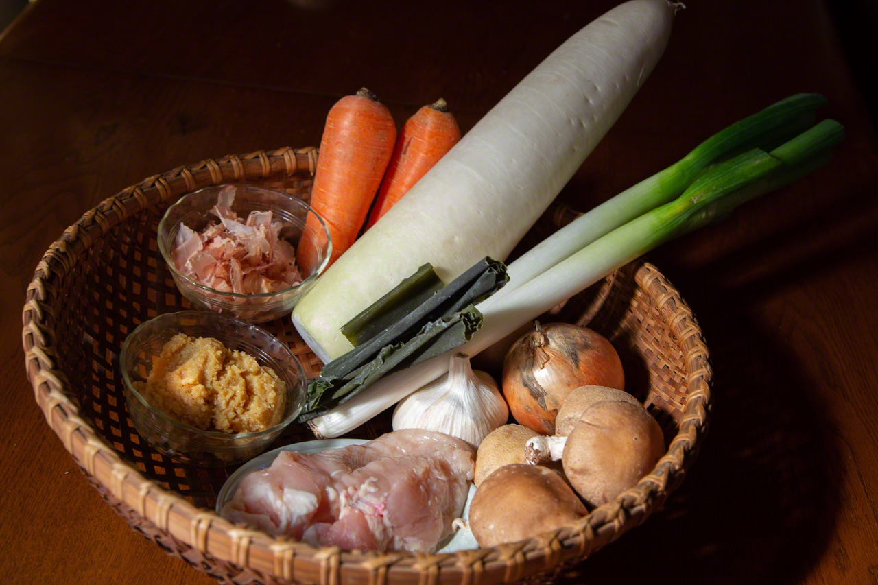 The ingredients of hyakusai nabe (clockwise from top): carrots, daikon radish, konbu, long onions, garlic, yellow onions, shiitake mushrooms , chicken, miso, and katsuo bushi (bonito flakes). (© Ōnishi Naruaki)
