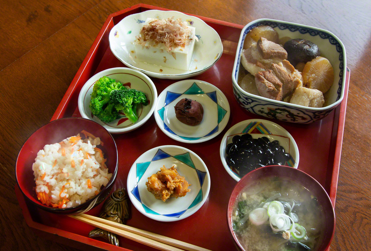 Eating a variety of dishes at each meal is one of the keys to longevity, according to Nagayama. The rice at left is mixed with carrots and flavored with butter and perilla oil. It is flanked on the right by Nagayama’s miso-pickled garlic. (© Ōnishi Naruaki)