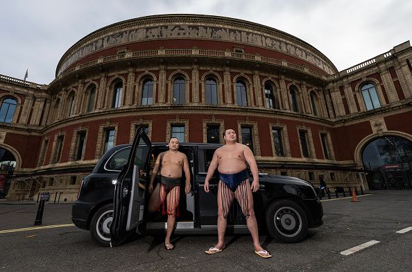 Kitanowaka (right) and a lower-ranked wrestler alight from a London cab in front of Royal Albert Hall in a photo taken as part of a publicity tour in December 2024 for the upcoming sumō exhibit. (© Getty Images)