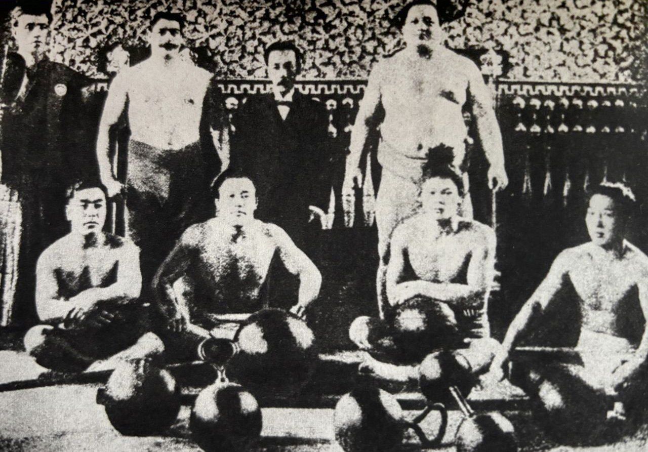 The Great Alexander (back row, second from left) matched strengths with Hitachiyama (back row, right) in 1907 in New York. Jūdōka and rikishi who were part of the group sit in the front row. (© Nagayama Satoshi)