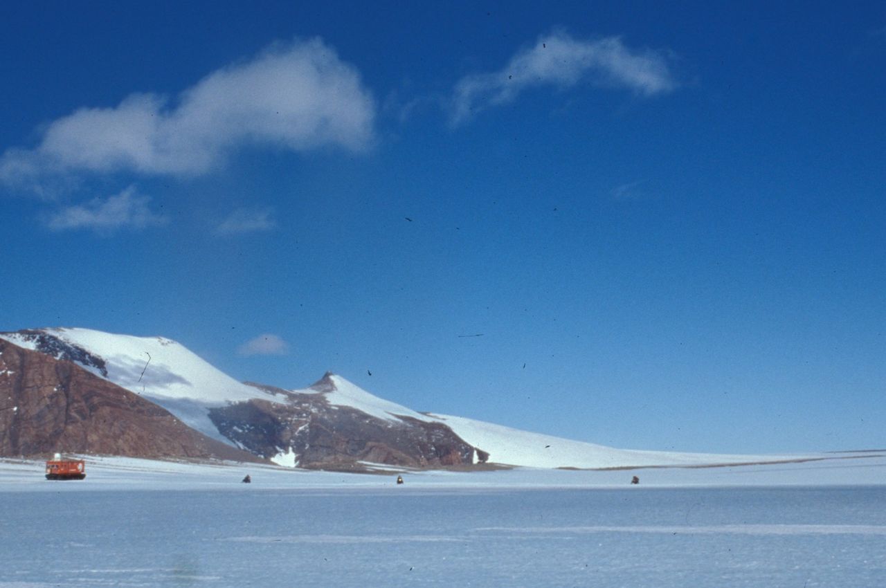 Three snowmobiles drive alongside a snowcat. (Courtesy the National Institute of Polar Research)