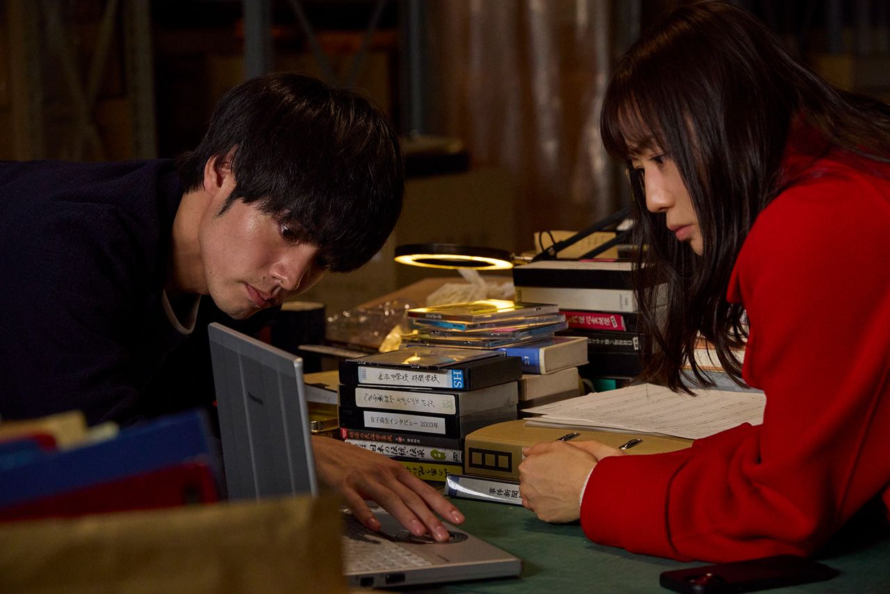 Yūsei (Akaso Eiji, left) and Chihiro (Kanno Miho) start their investigation in the magazine’s basement archives. (© 2025 Kinki chihō no aru basho ni tsuite Production Committee)