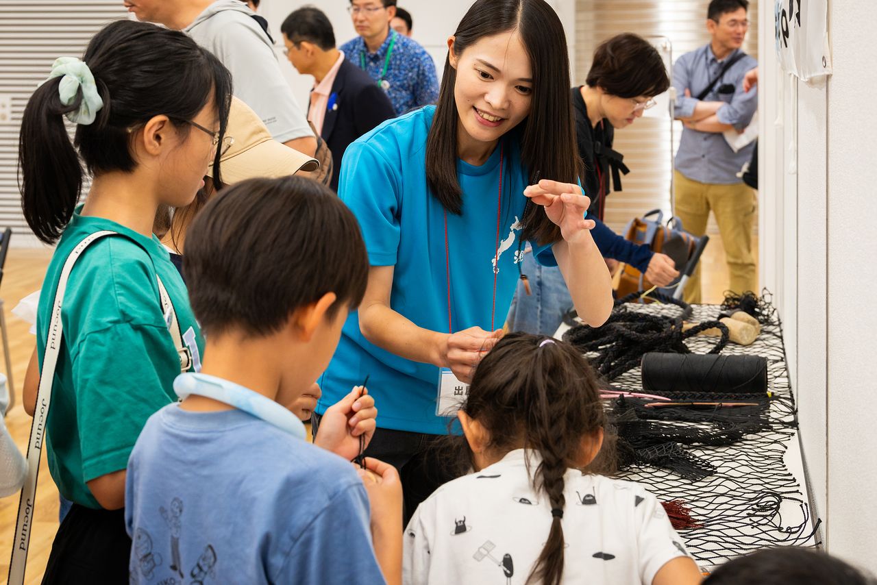 Kanazawa presents the tools of her trade to children interested in fishing. (© Nippon.com)