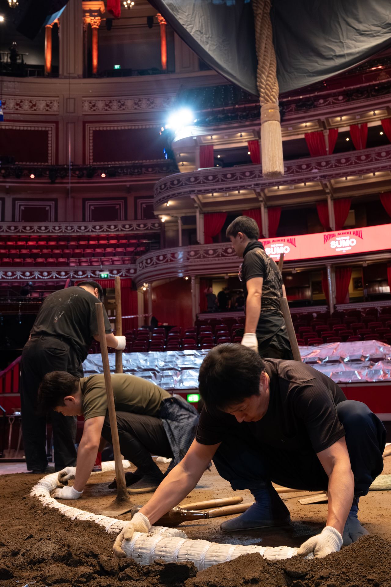 Workers lay down the plastic tawara bales marking the edge of the ring. (© Tony McNicol)