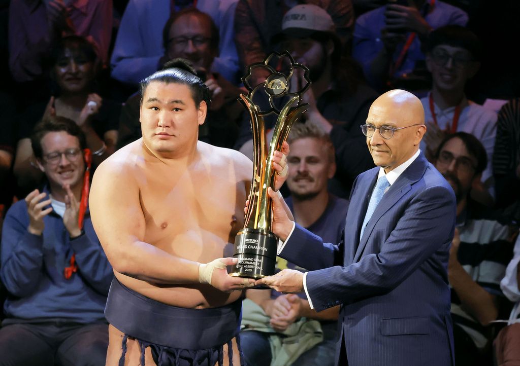 Hōshōryū, left, hoists the trophy after defeating Ōnosato to win the tournament on October 19 at London’s Royal Albert Hall. (© Kyōdō)