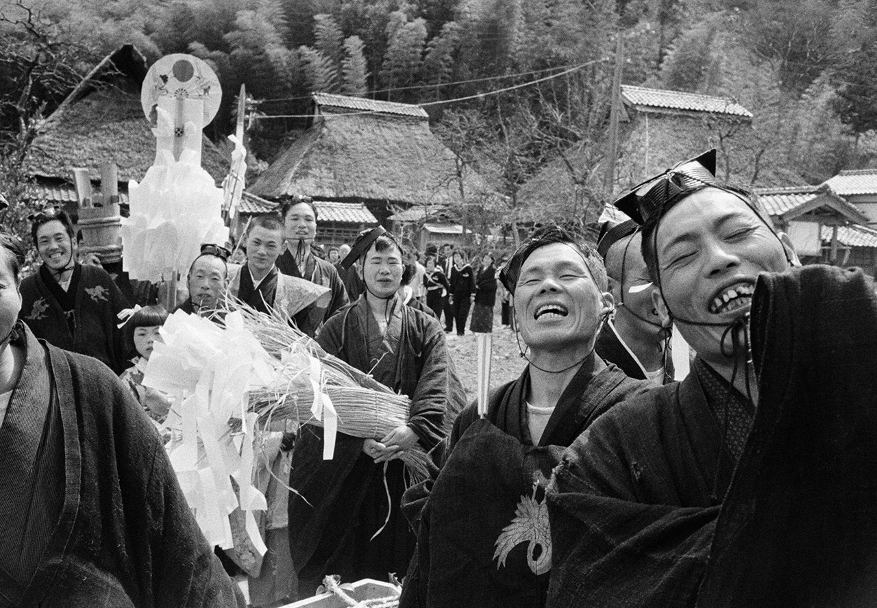 Muradachi: A scene from Kunitsu Shrine, a local shrine festival. After a festive meal hosted by the lead parishioner, merry worshipers carry a gohei pole decorated with paper streamers back to the shrine. Fukui Prefecture, 1973. (© Haga Hideo)