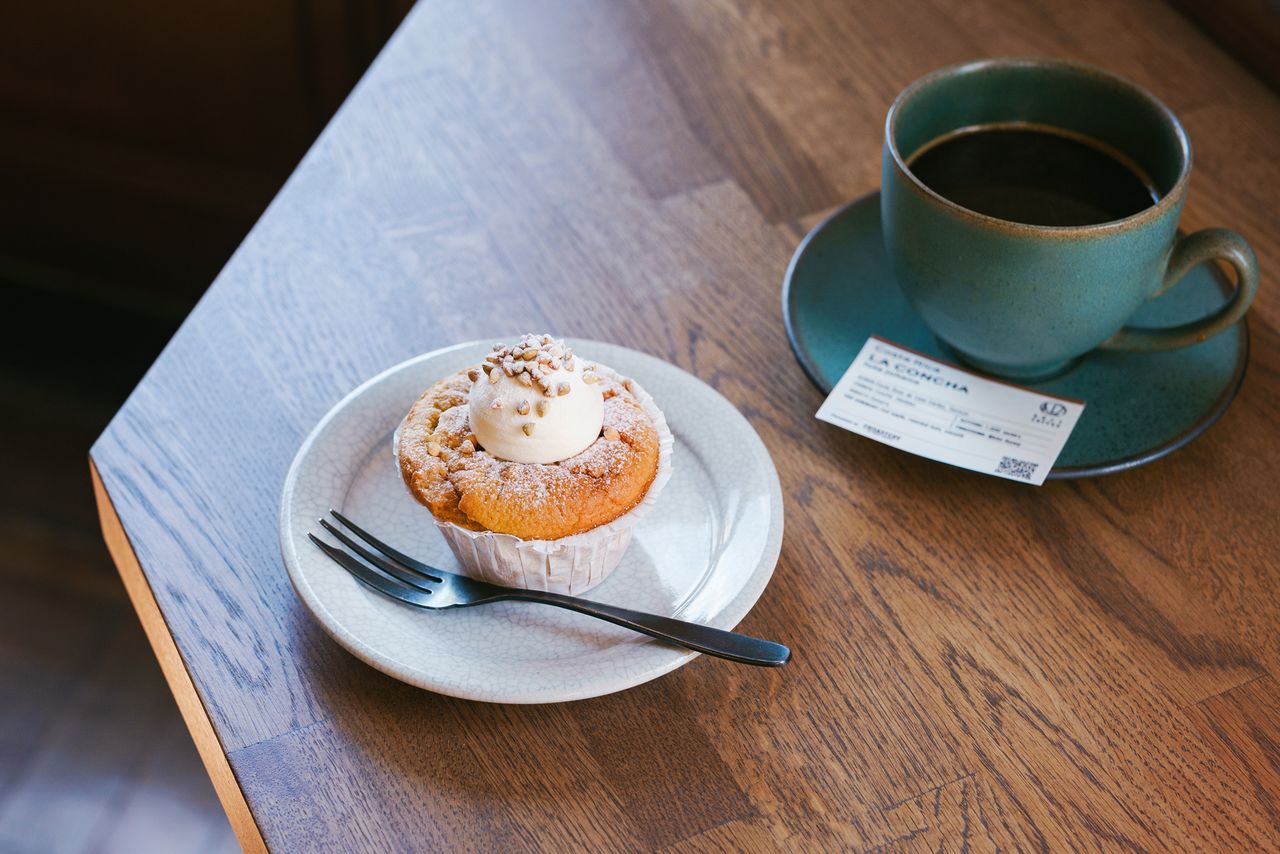 An Americano coffee and a delectable soba-flour chiffon cupcake. A card placed on the saucer gives details of the coffee beans, including place of origin. (© Kawaguchi Yōko)