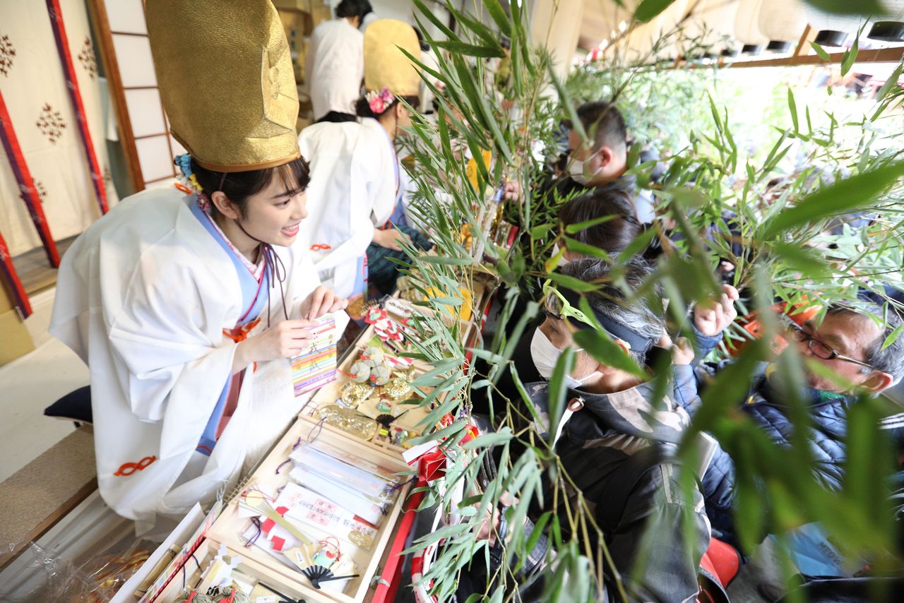 Women in distinctive hats give out the lucky bamboo. (© Jiji)