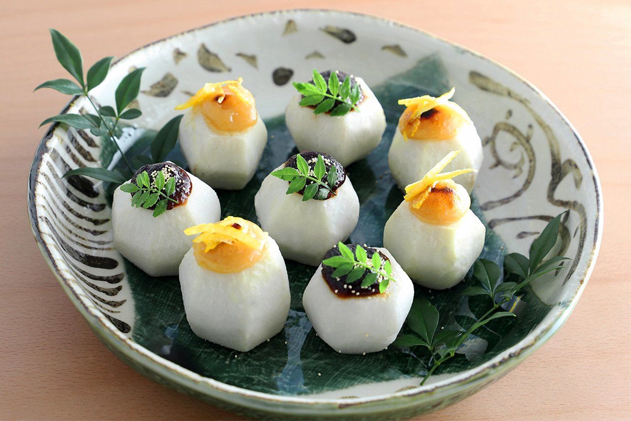 Steamed satoimo topped with brilliant yellow yuzu and greens on miso. (© Pixta)