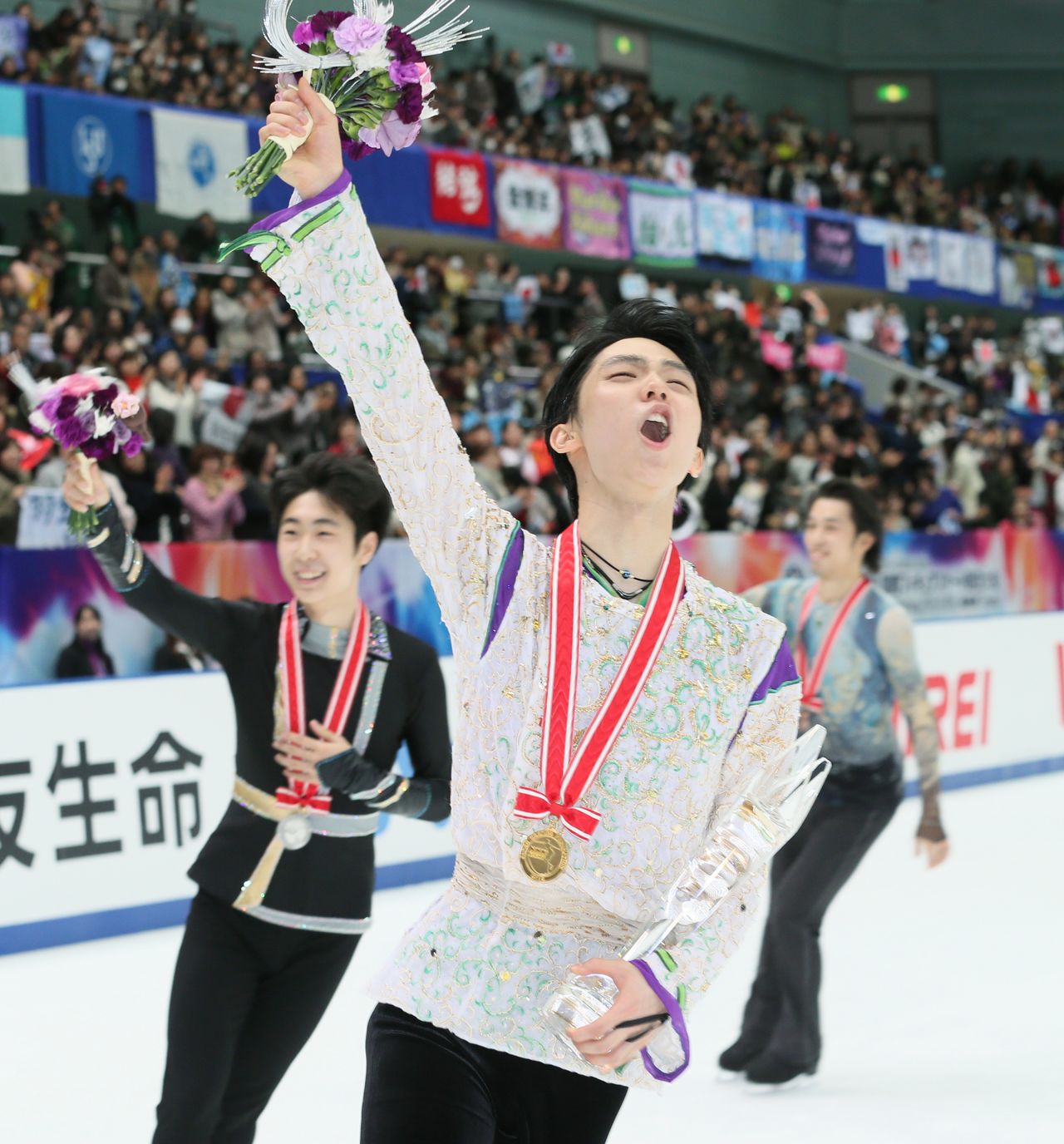 Hanyū Yuzuru (center) celebrates finishing first in the Grand Prix NHK Trophy. Behind him are second-place finisher Jin Boyang from China (left) and Mura Takahito of Japan (right), who finished third. (© Jiji)