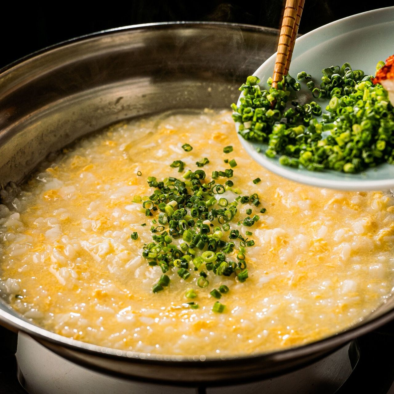 Savoring the broth of fugu hot pot by adding rice to make zōsui porridge. (Courtesy Tsukiji Tentake)