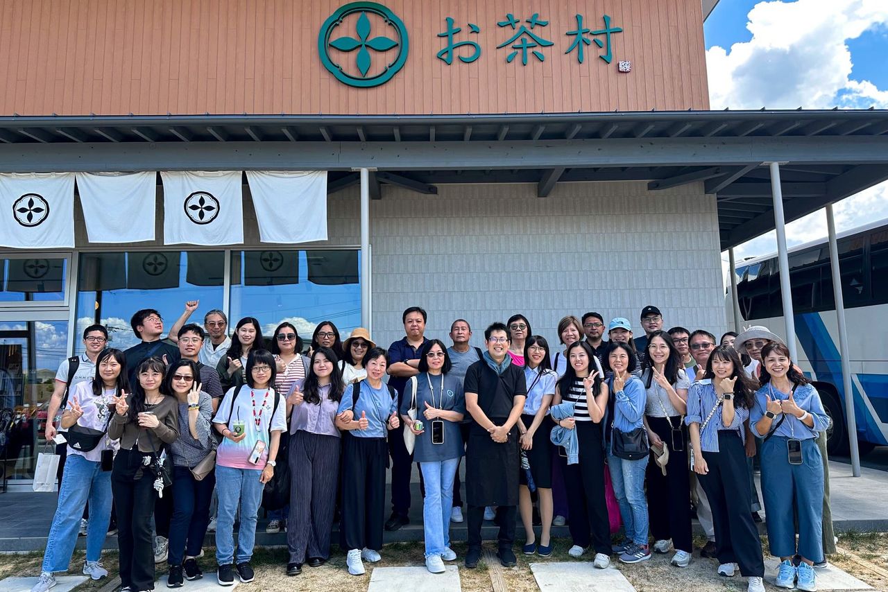 Ōishi Ken’ichi (front row center, in the black shirt) welcomes international tourists at his farm’s sales shop and cafe. (Courtesy Ōishi Tea Factory)