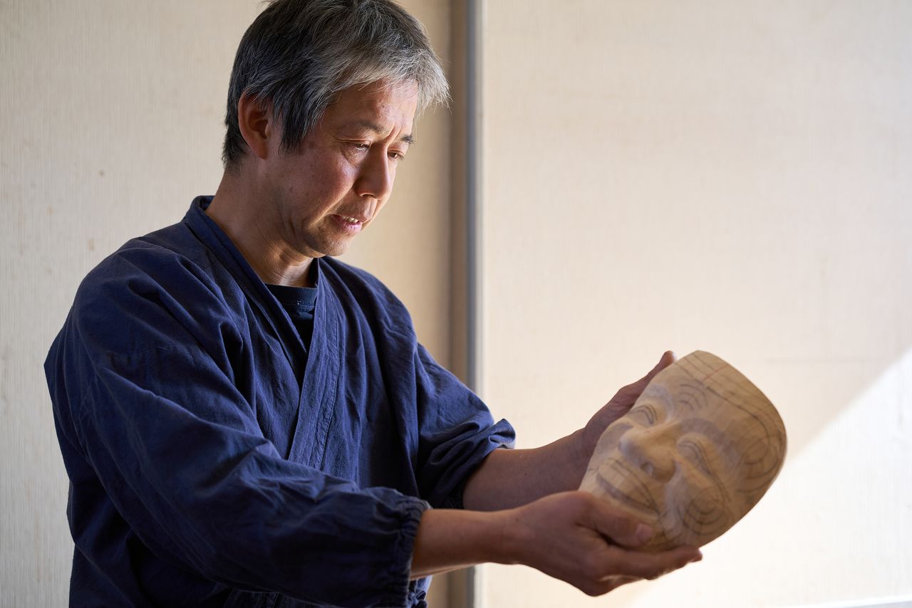 Kitazawa examining an okina mask in progress from different angles. (© Kuratani Kiyofumi)