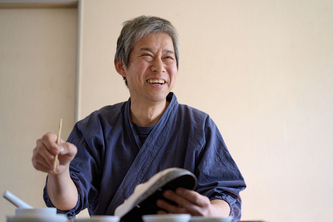 Kitazawa smiles while working on a waka-onna (young-woman) mask, vowing to continue honing his craft. (© Kuratani Kiyofumi)
