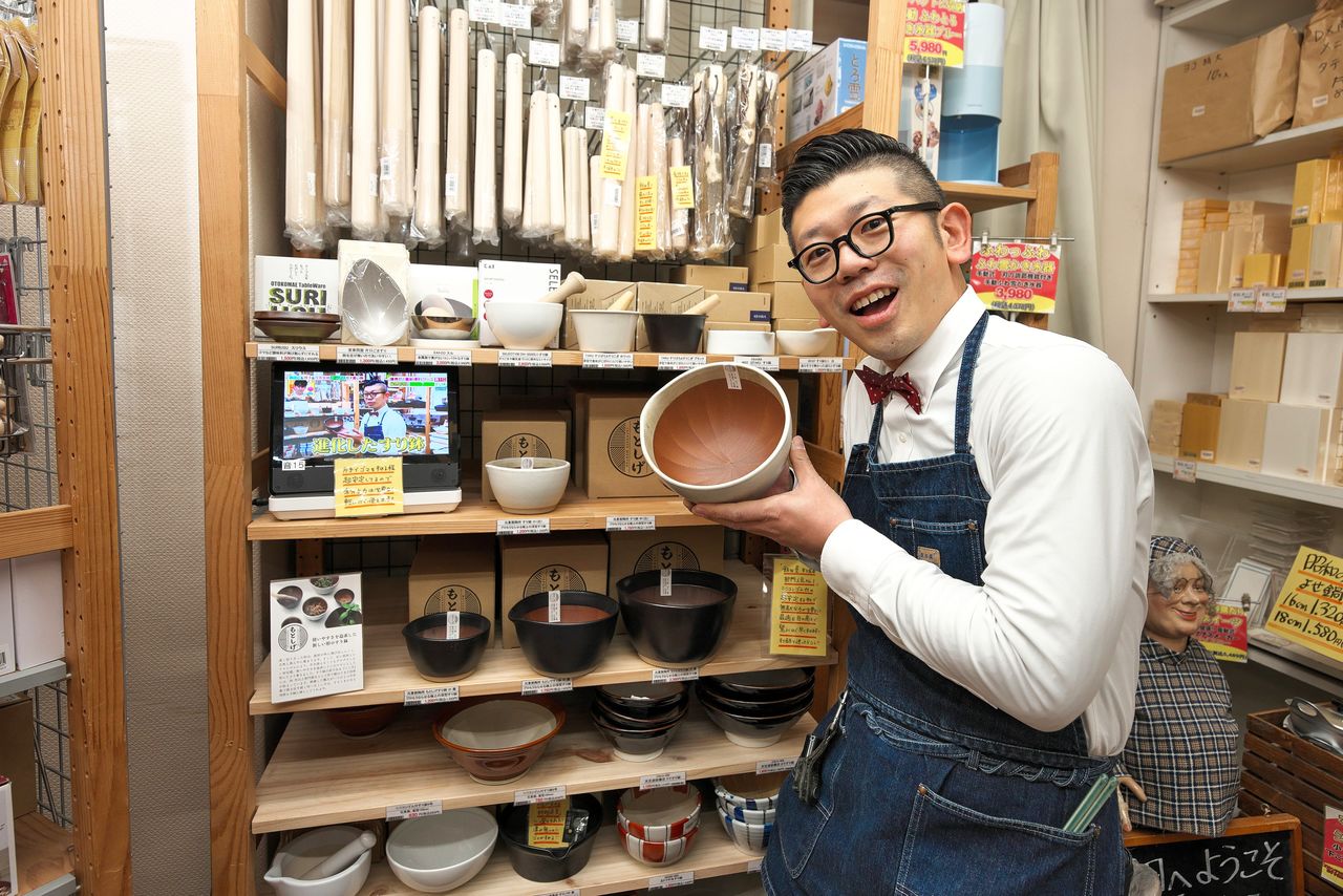 Iida Yūta, the sixth-generation owner of Iidaya, in the plentifully stocked suribachi earthenware mortar section. (© Nomura Kazuyuki)