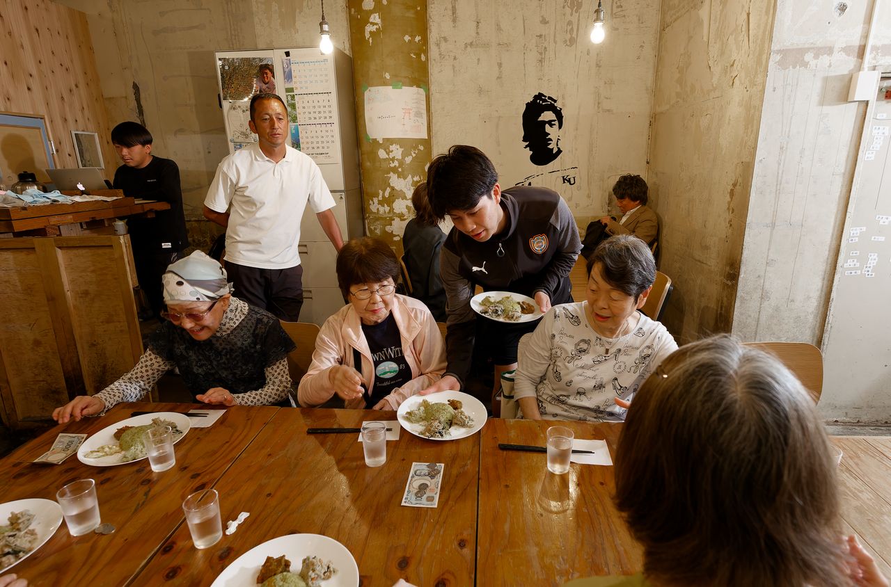 Students serve the meals at the Takeyama Kitchen dining hall. They grow many of the vegetables themselves at a nearby farm. (© Nomura Kazuyuki)