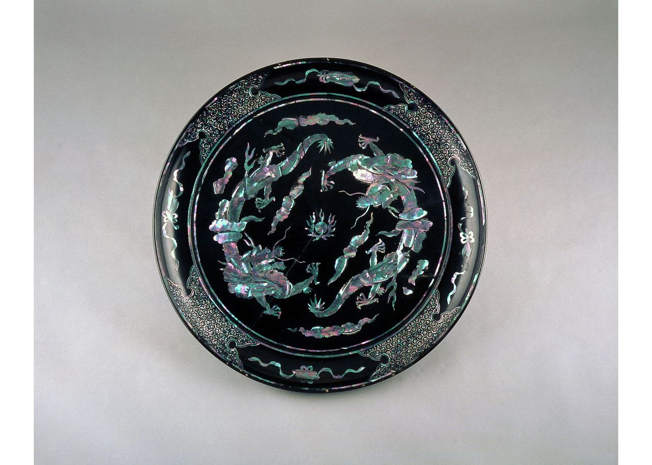 Large plate tray with unryū cloud dragons in mother-of-pearl on black lacquer. This piece dates from the late eighteenth or early nineteenth century. The auspicious design shows a pair of dragons emerging from clouds bearing wish-fulfilling jewels. (In the collection of the Urasoe Art Museum)