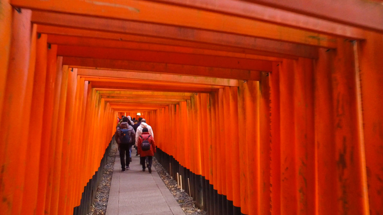 Shrine visitors head up a path lined by the <em>senbon-torii</em> at Fushimi Inari Taisha.
