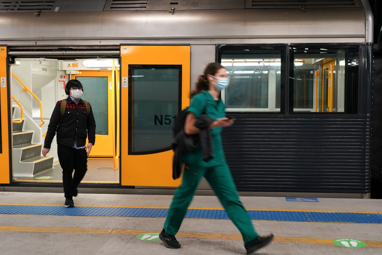 FILE PHOTO: Passengers wearing protective face masks walk across a train platform at the quiet Central Station in the city centre during a lockdown to curb the spread of a coronavirus disease (COVID-19) outbreak in Sydney, Australia, August 12, 2021. REUTERS/Loren Elliott