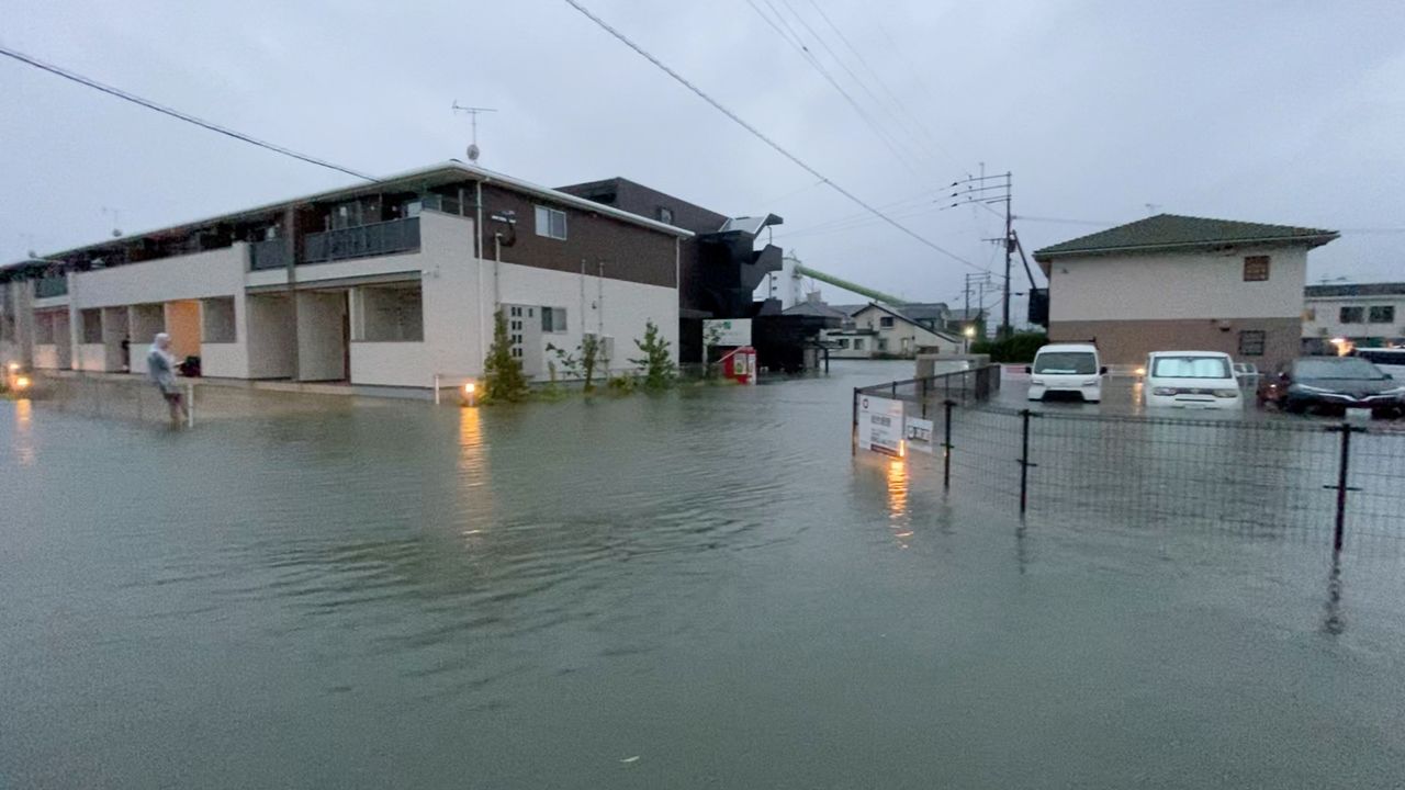 A person stands at a flooded street during heavy rain in Kurume, Fukuoka Prefecture, Japan August 14, 2021, in this still image taken from video provided on social media. Mandatory credit TWITTER @NAPSPANS/via REUTERS