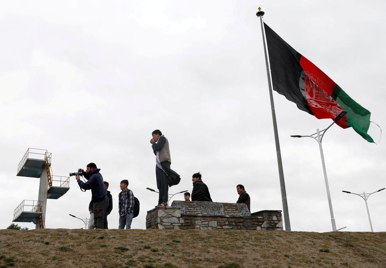 FILE PHOTO: Youths take pictures next to an Afghan flag on a hilltop overlooking Kabul, Afghanistan, April 15, 2021. REUTERS/Mohammad Ismail/File Photo
