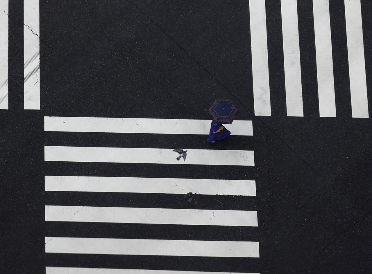 FILE PHOTO: A woman walks on crosswalk in the rain amid the coronavirus disease (COVID-19) outbreak in Tokyo, Japan, August 7, 2021. REUTERS/Kim Kyung-Hoon