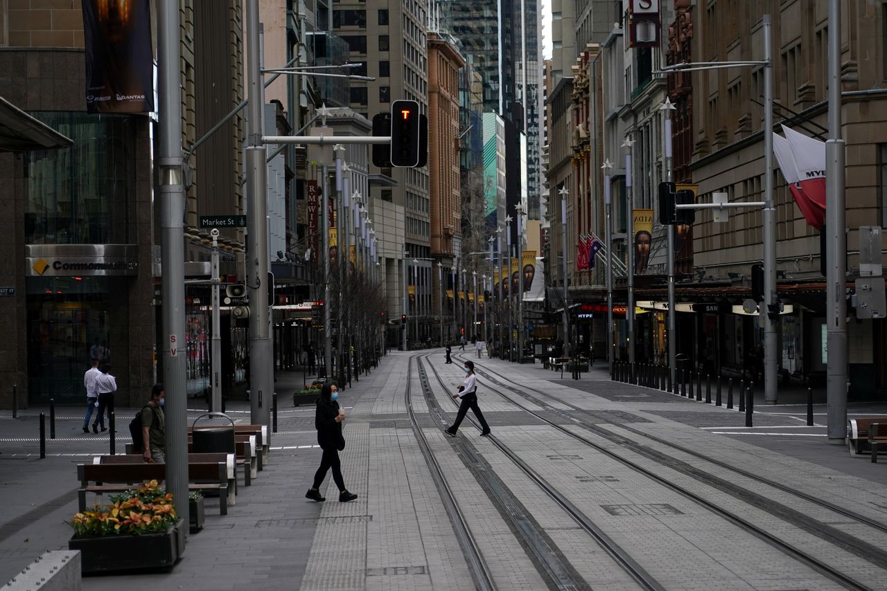 FILE POTO: People in protective face masks walk through the quiet city centre during a lockdown to curb the spread of a coronavirus disease (COVID-19) outbreak in Sydney, Australia, July 28, 2021. REUTERS/Loren Elliott