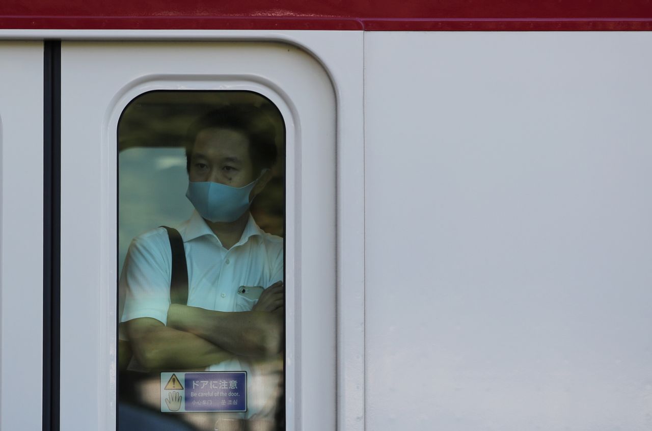 FILE PHOTO: A man wearing a protective mask rides a train, amid the coronavirus disease (COVID-19) outbreak, in Tokyo, Japan, August 10, 2021. REUTERS/Kim Kyung-Hoon