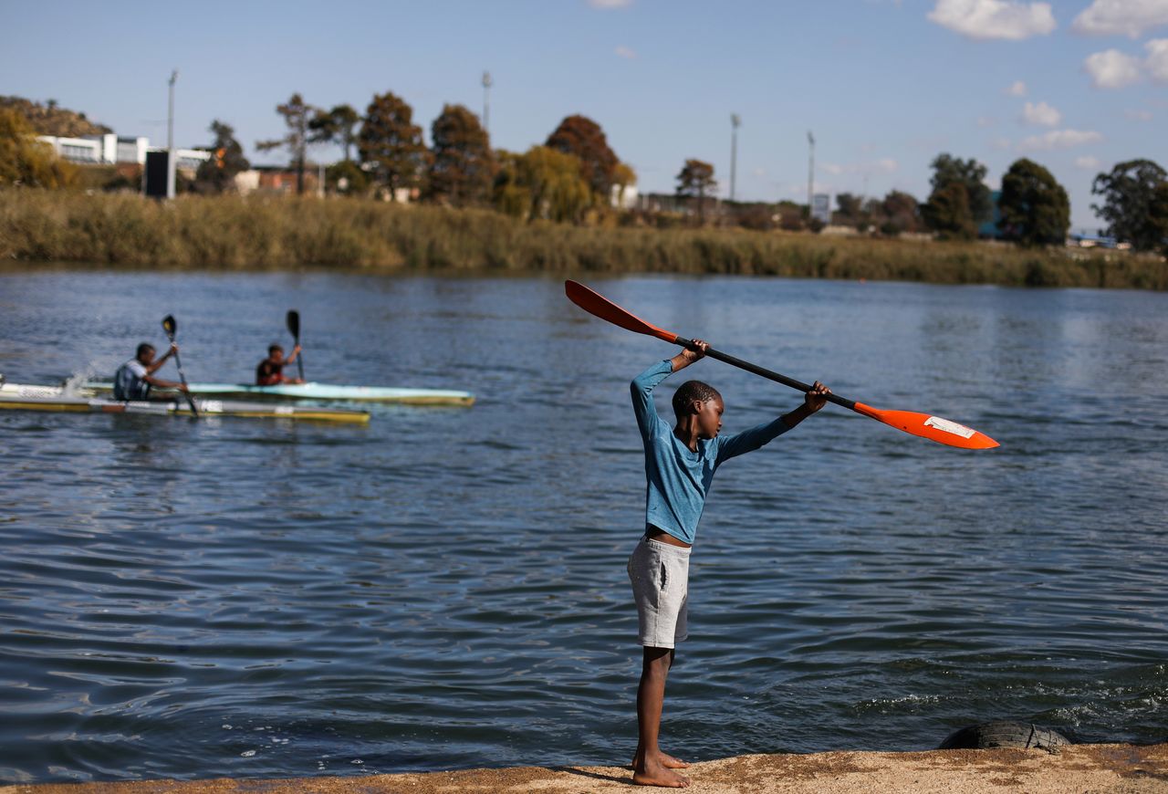 A boy imitates a group of canoeists at the Orlando Dam in Soweto, South Africa, June 12, 2021.  REUTERS/Siphiwe Sibeko