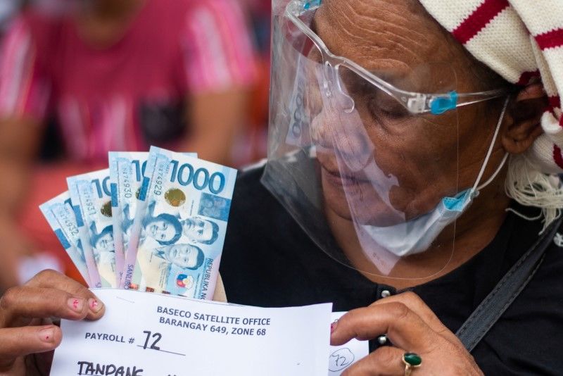 A woman receives cash assistance from the government following the imposition of two-week lockdown to prevent the spread of the coronavirus Delta variant, at an elementary school in Manila, Philippines, August 11, 2021. REUTERS/Lisa Marie David