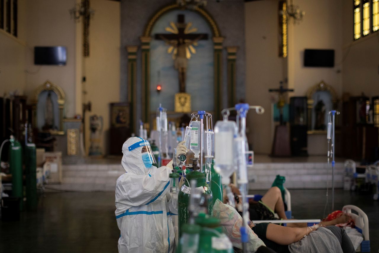 A health worker checks on a coronavirus disease (COVID-19) patient admitted in the chapel of Quezon City General Hospital turned into a COVID-19 ward amid rising infections, in Quezon City, Metro Manila, Philippines, August 20, 2021. REUTERS/Eloisa Lopez