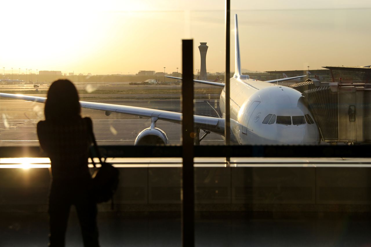 FILE PHOTO-A woman takes pictures in front of an airplane at the Beijing Capital International Airport in Beijing, China May 9, 2021. REUTERS/Tingshu Wang