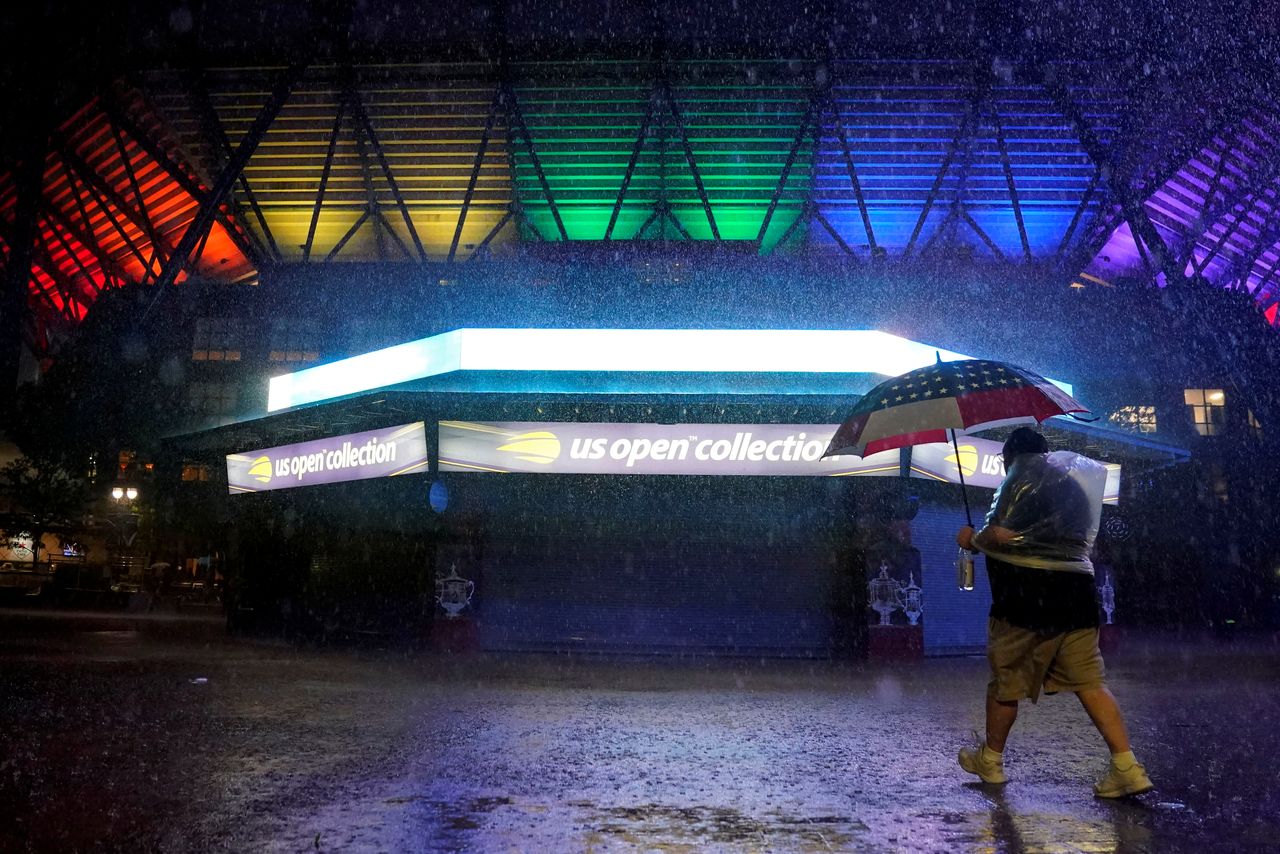 FILE PHOTO: A man walks by the flooded pavilion along Arthur Ashe Stadium on day three of the 2021 U.S. Open tennis tournament at USTA Billie Jean King National Tennis Center in Flushing, New York, U.S. September 1, 2021. Danielle Parhizkaran-USA TODAY Sports via REUTERS MANDATORY CREDIT